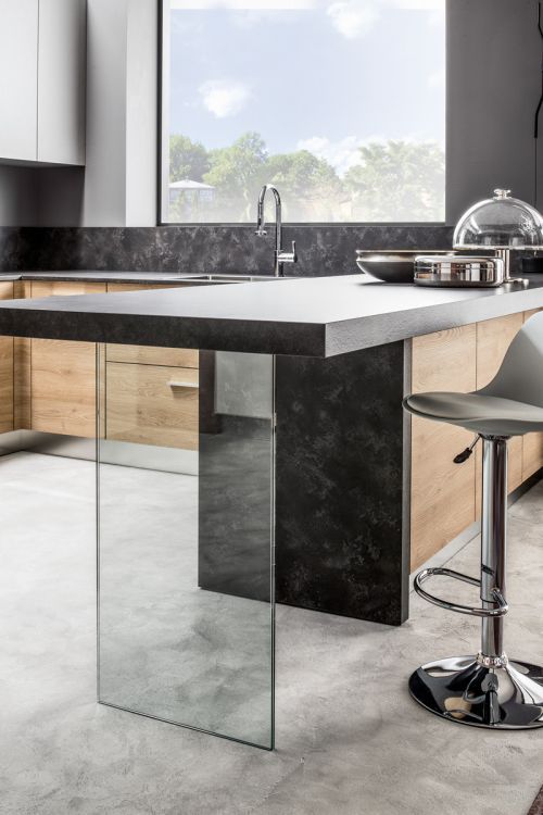 Isola cucina moderna con finitura in marmo bianco e nero e sgabello da bar accanto a una finestra.