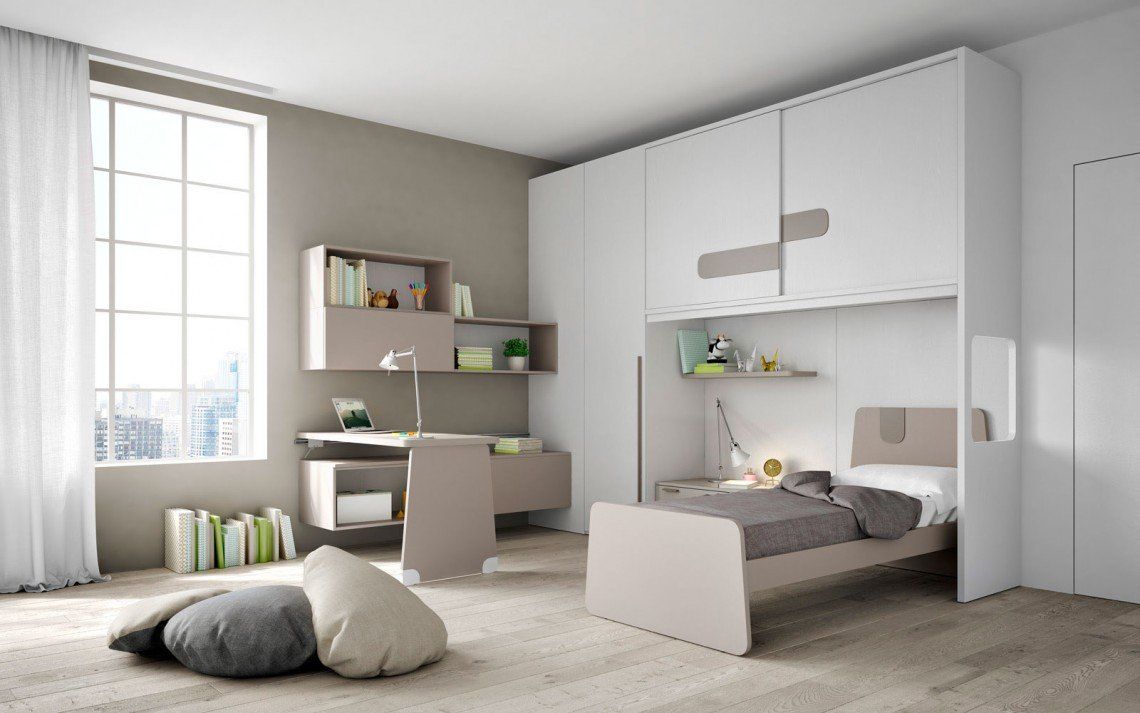 Camera da letto luminosa e minimalista con scrivania, vani contenitori in stile loft e un letto grigio chiaro accanto a una finestra.