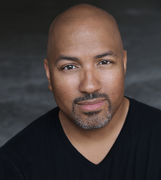 A bald man with a beard is wearing a black shirt