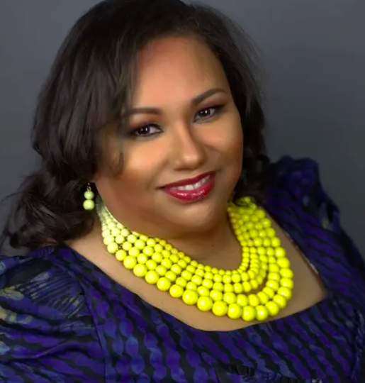 A woman wearing a blue dress and a yellow necklace