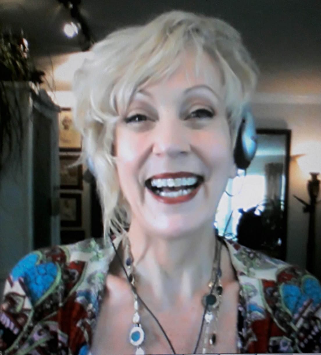 A woman wearing headphones and a necklace smiles for the camera