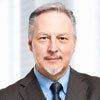 A man in a suit and tie is looking at the camera.
