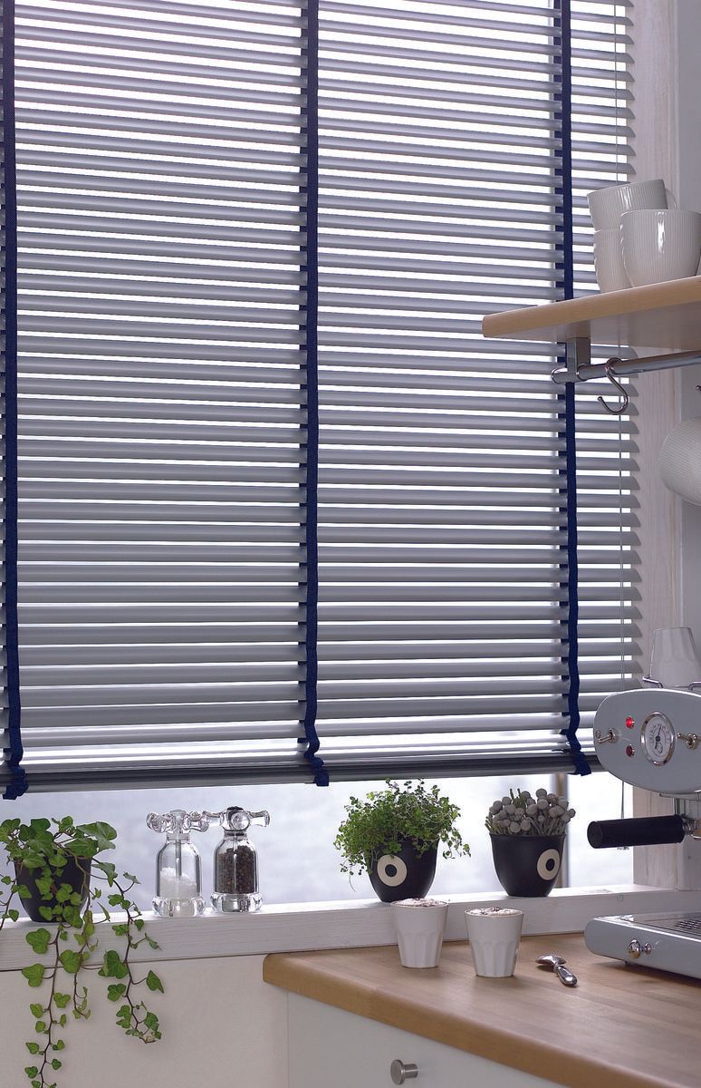 Kitchen window with blue blinds, plants, and coffee machine.