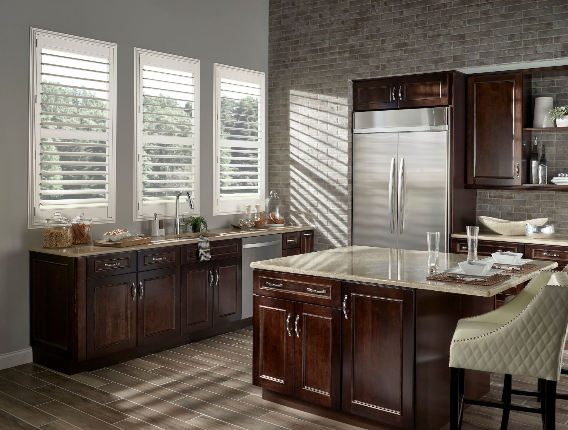Kitchen with dark wood cabinets, stainless steel refrigerator, and island with granite countertop. Windows with shutters.