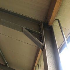 Een metalen I-balk, verbonden met een verticale pilaar door middel van een stalen verbindingsplaat en zware bouten.
