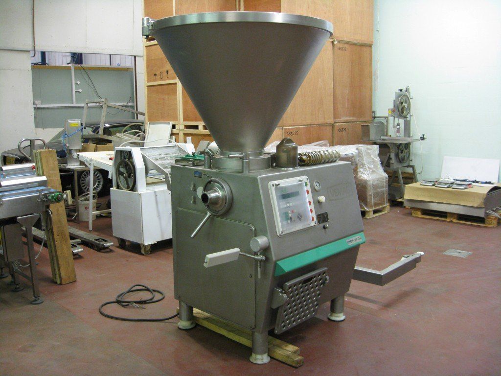 Sausage stuffer machine in industrial setting; stainless steel with green accents; a large hopper on top.