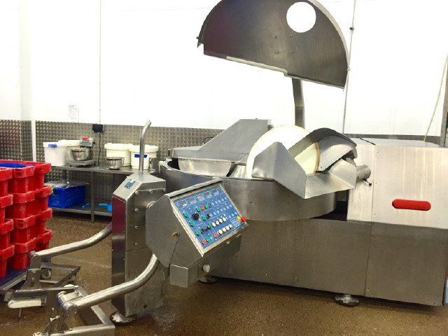 Meat processing machine in a clean, industrial setting with control panel.