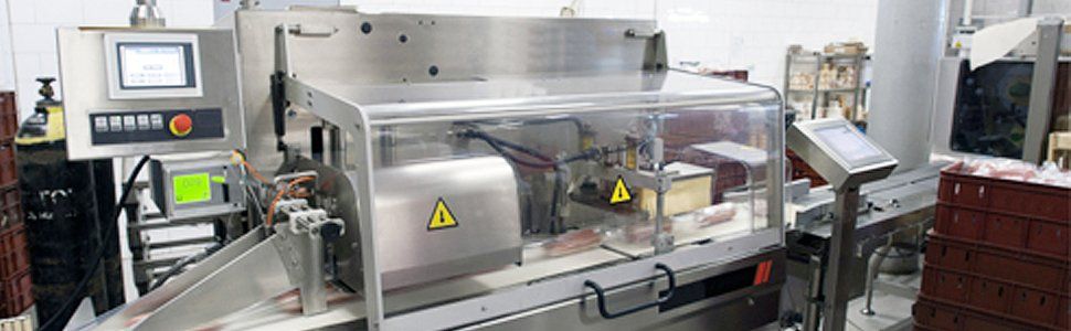 Industrial machine with control panels and clear protective cover, warning signs visible.