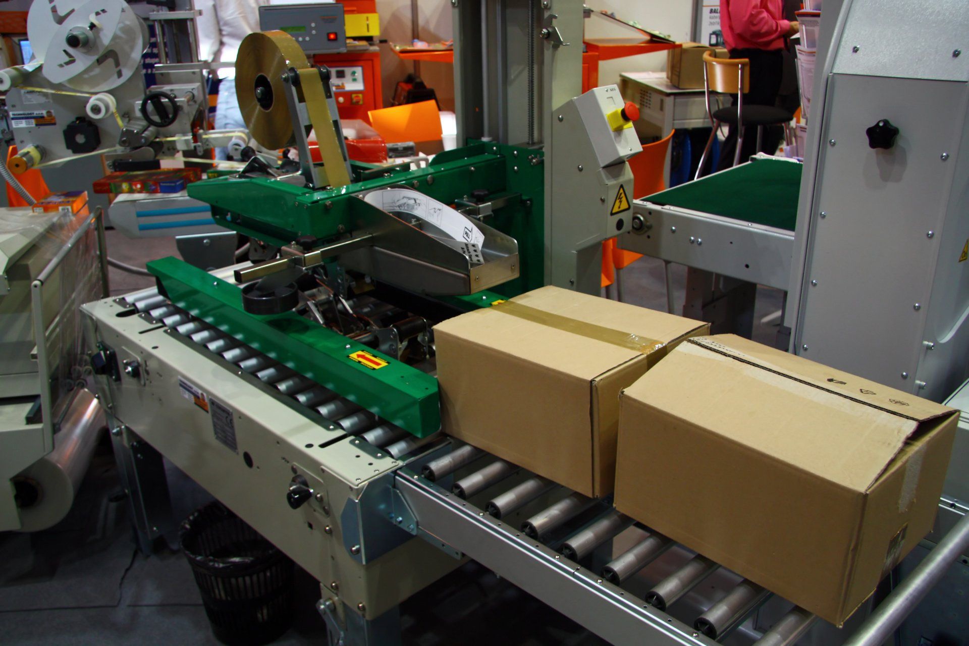 Two cardboard boxes are on a conveyor belt in a factory