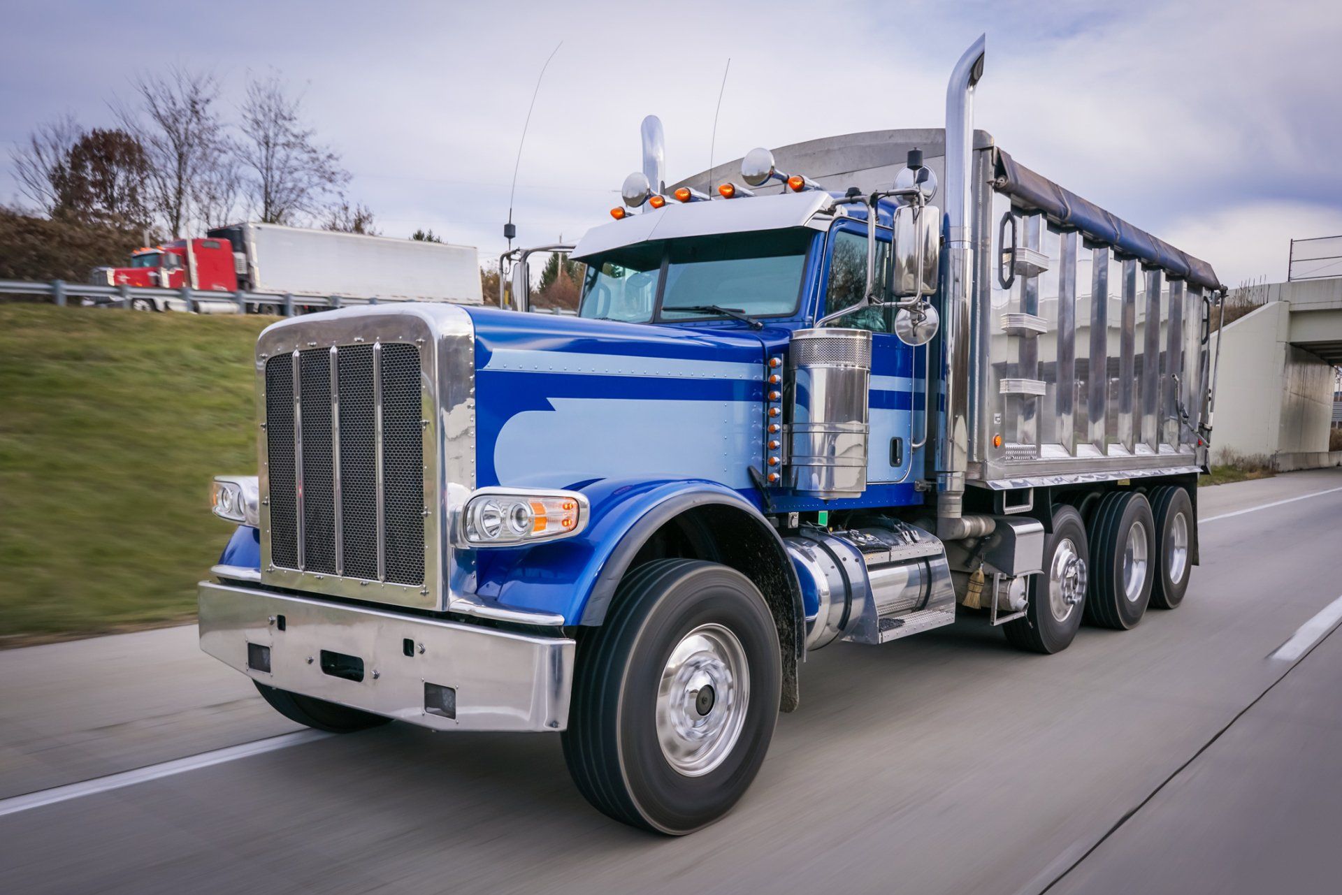 Blue dump truck driving on a highway.