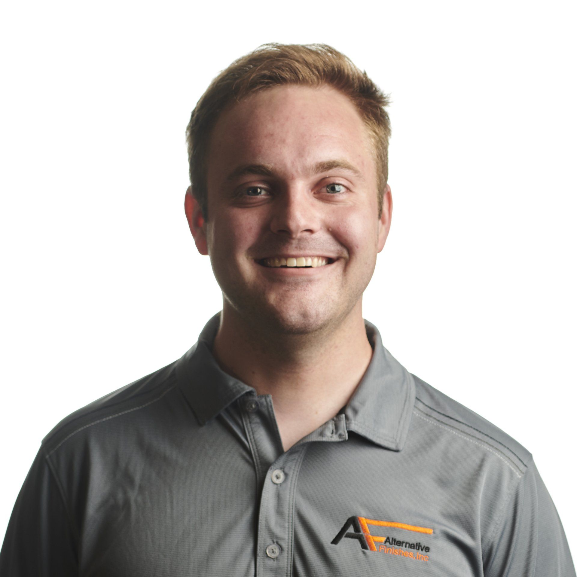 Smiling man wearing a grey polo shirt with a logo, against a white background.