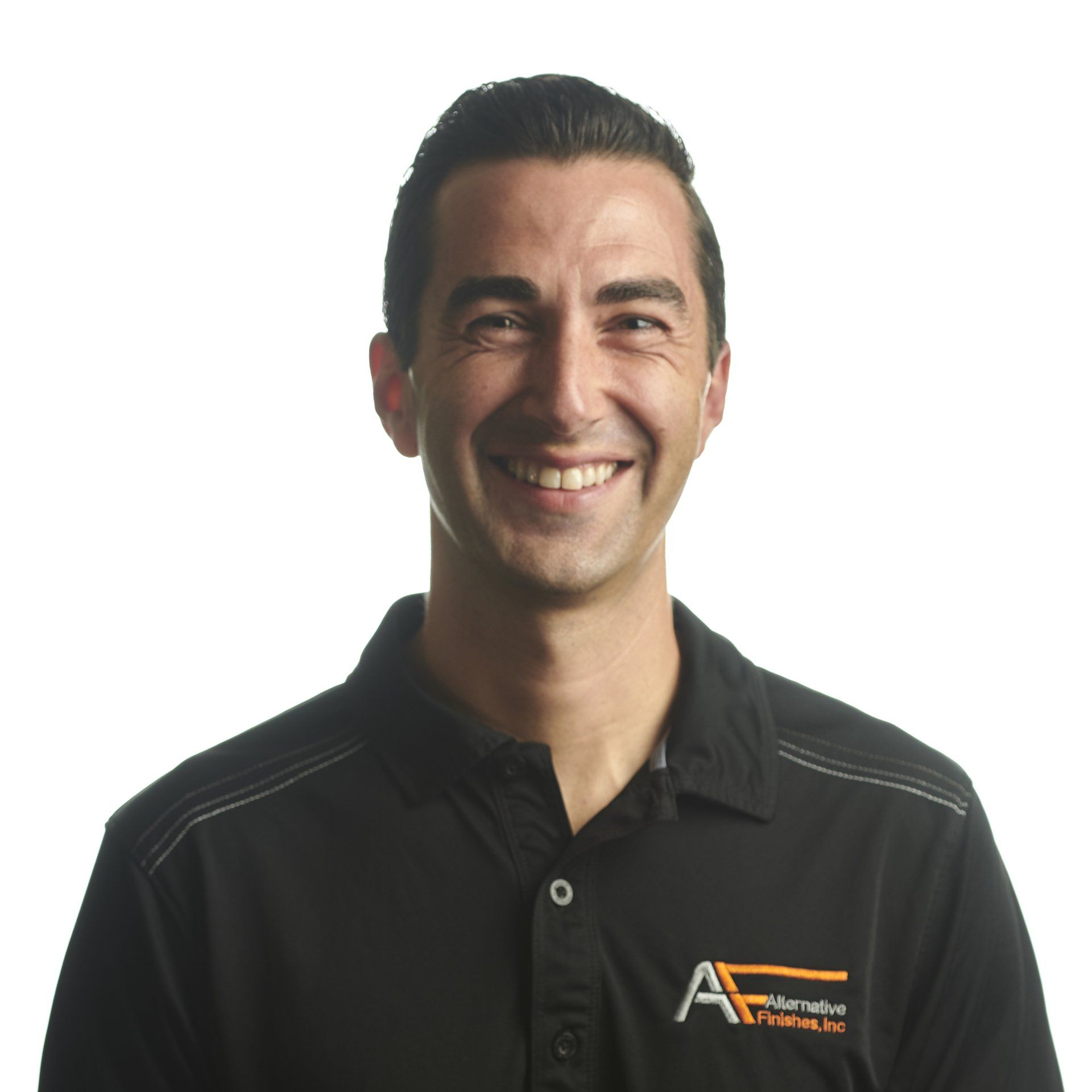 Man with short brown hair smiling, wearing a black collared shirt with orange logo.
