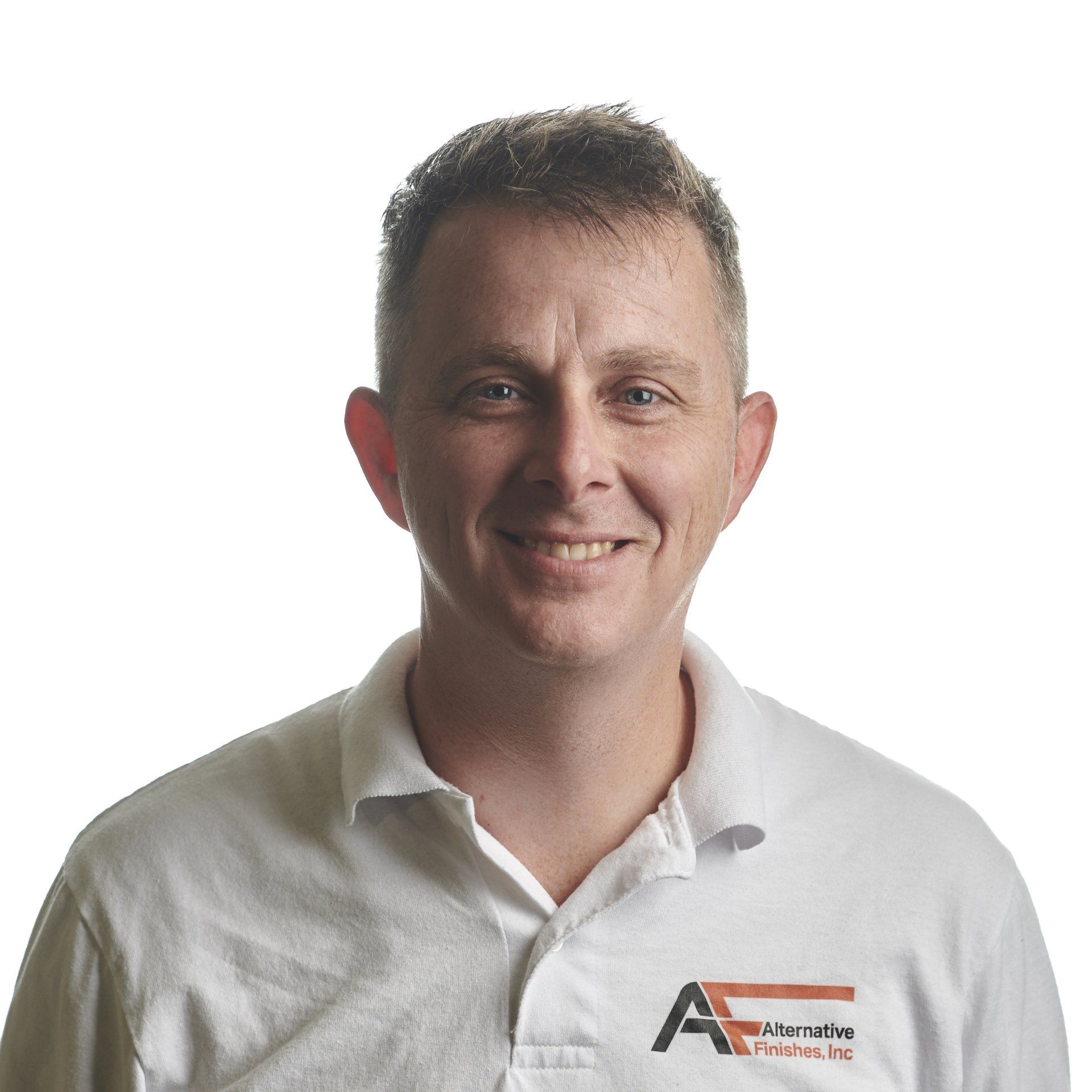 Man in a white polo shirt smiles at the camera. He has short, dark hair and is in front of a white background.