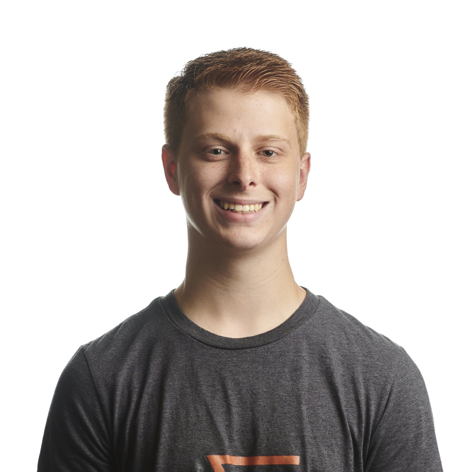 Young person with reddish hair smiles in a gray t-shirt against a white background.