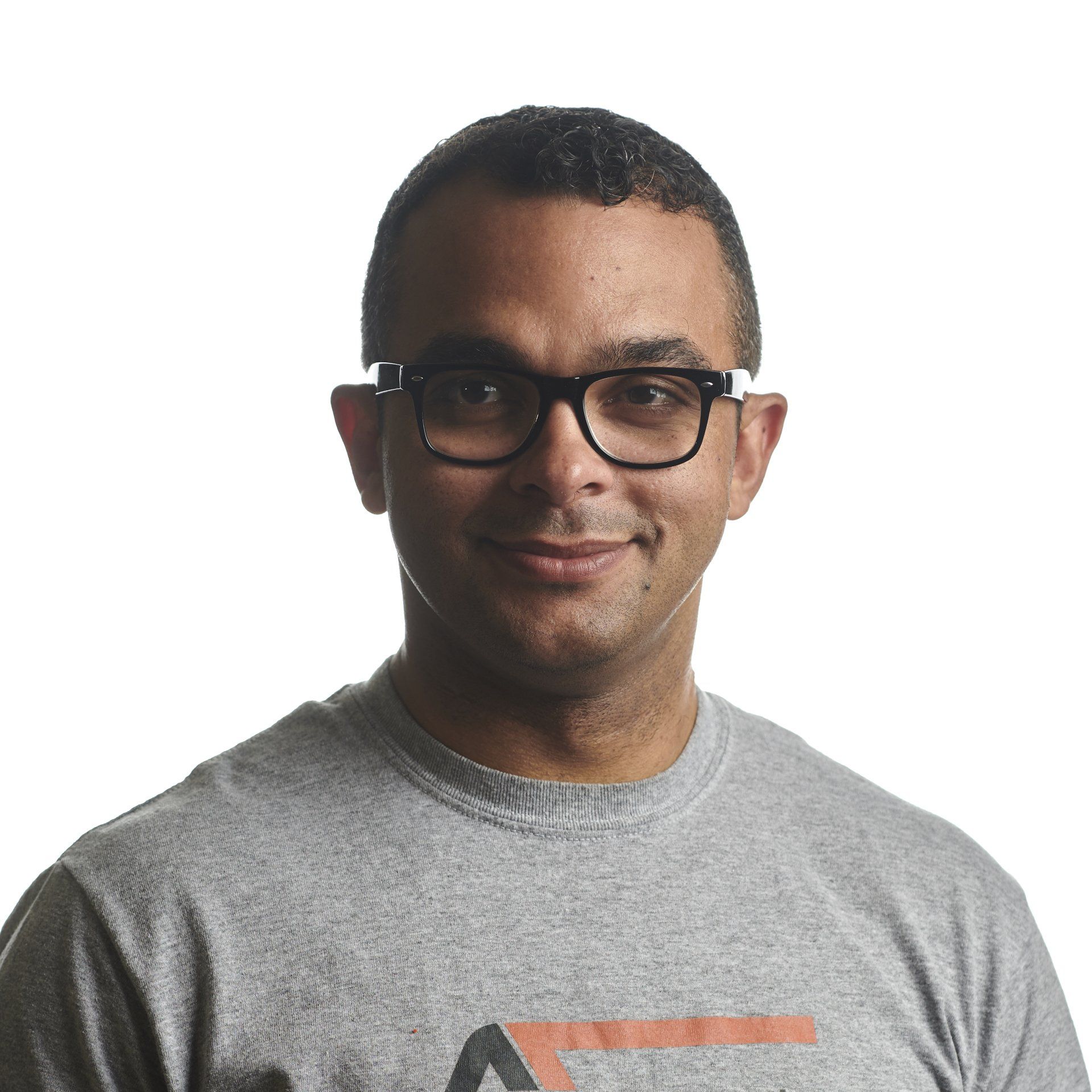Person wearing glasses, smiling, wearing a gray t-shirt. White background.