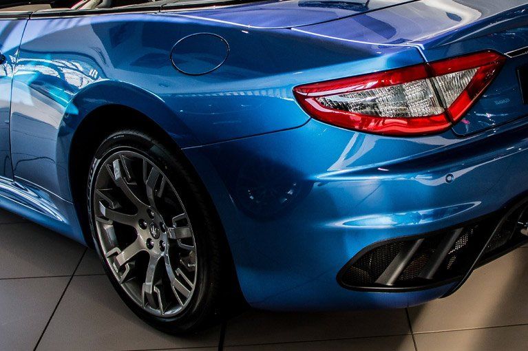Blue Maserati convertible car rear quarter panel and wheel.