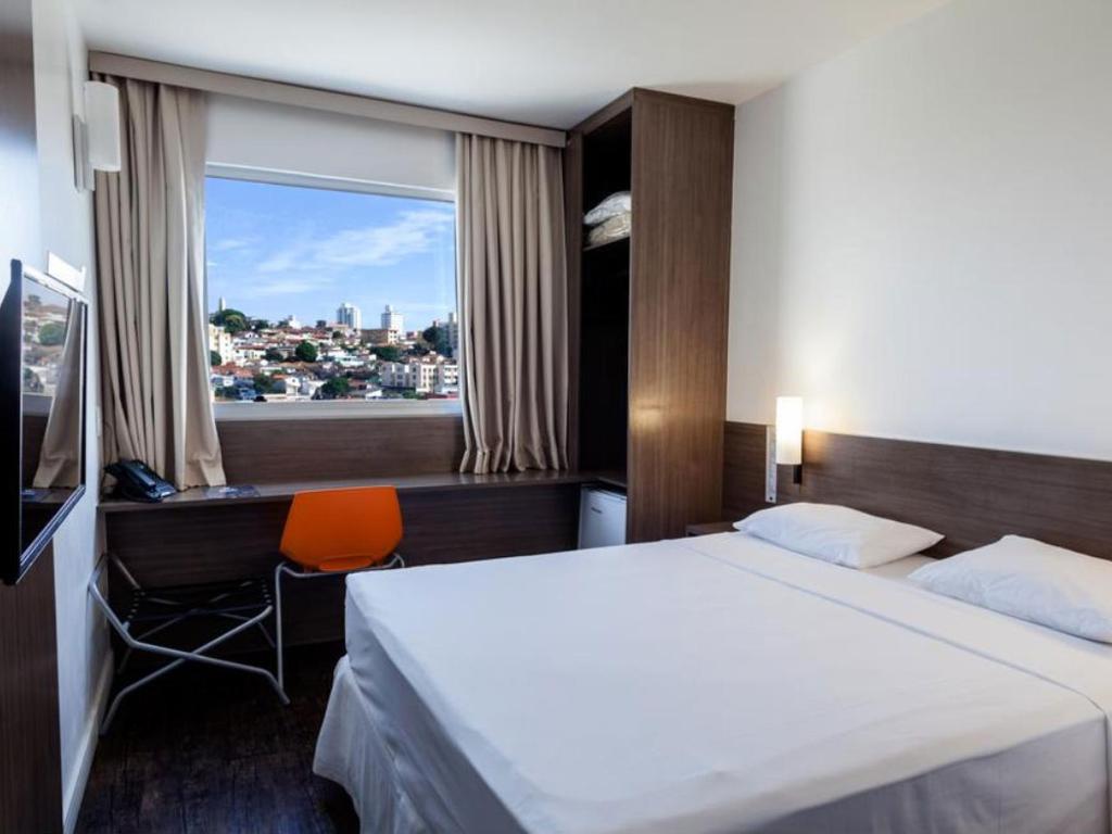 Um quarto de hotel com uma cama grande e uma janela grande