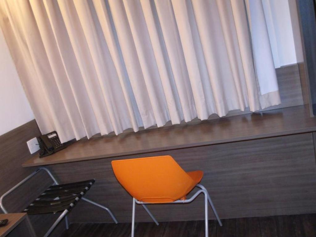 Uma cadeira está em frente a uma janela em um quarto de hotel.