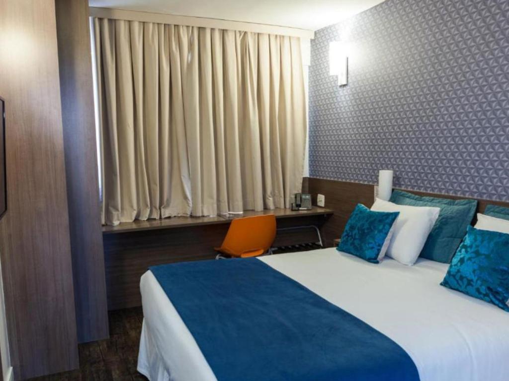 Um quarto de hotel com uma cama, escrivaninha e cadeira