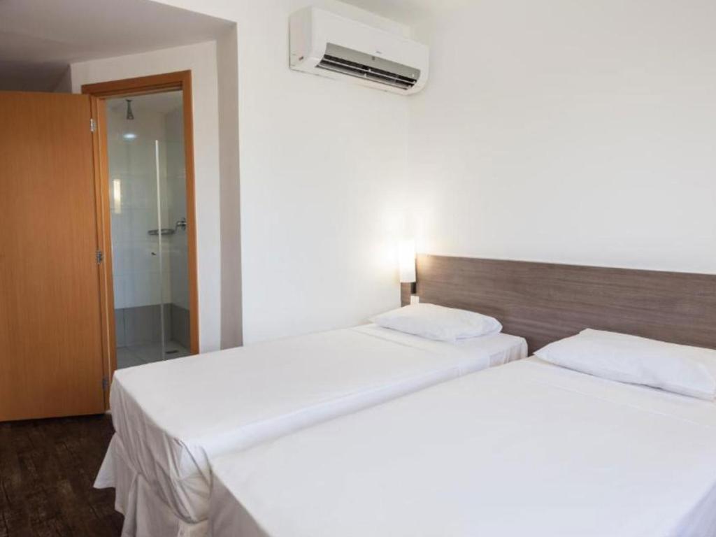 Um quarto de hotel com duas camas e um ar condicionado na parede.