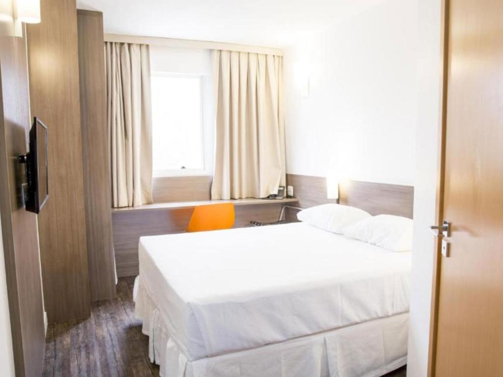 Um quarto de hotel com uma cama king size, escrivaninha e televisão.