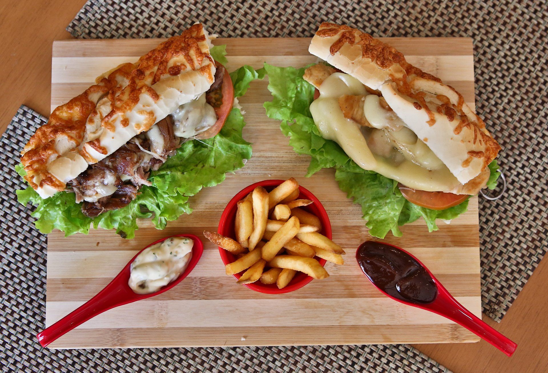 Dois sanduíches sub e batatas fritas em uma tábua de corte de madeira