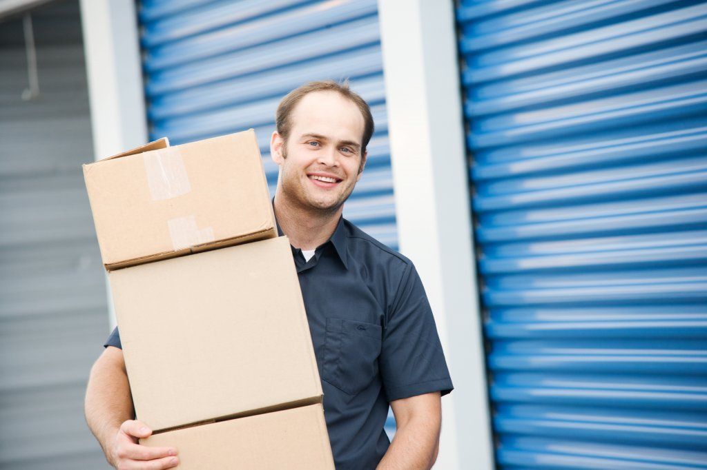 : A picture of a happy person putting a box in a storage unit.