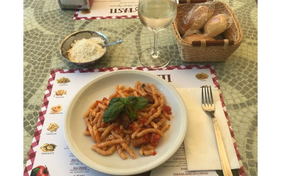 Tavolo apparecchiato con piatto di pasta al pomodoro e basilico