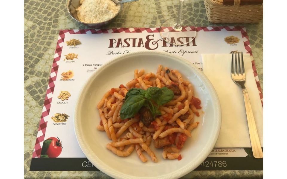 Tavolo apparecchiato con piatto di pasta al pomodoro e basilico