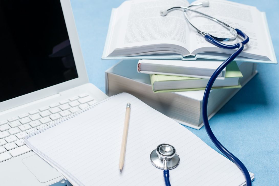 computer, block notes, stetoscopio e tanti libri