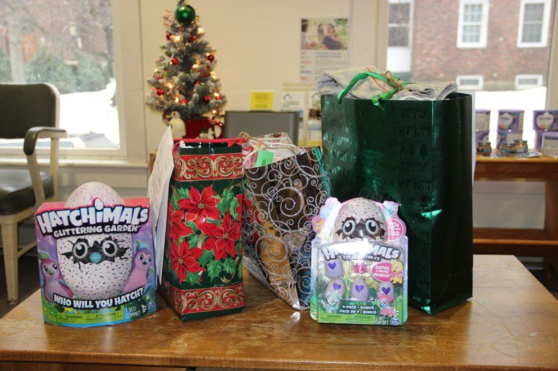 Three hatchimals toys are sitting on a wooden table in front of a christmas tree.
