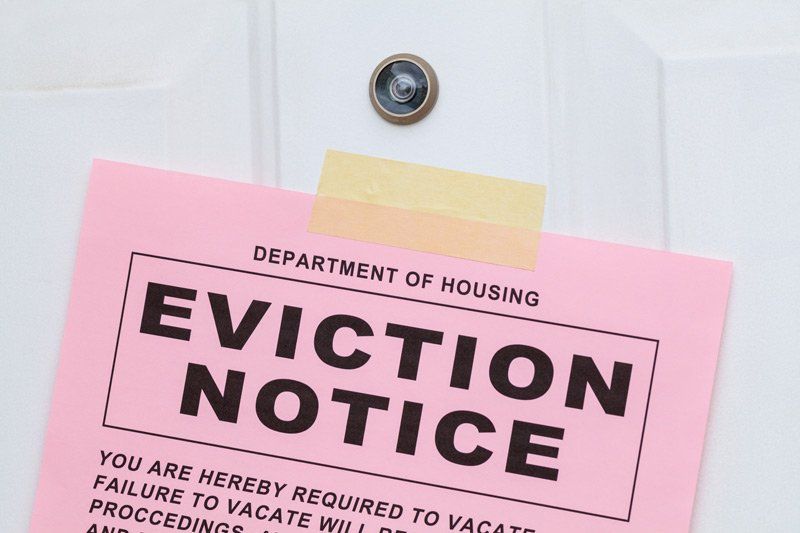 A pink eviction notice is taped to a door