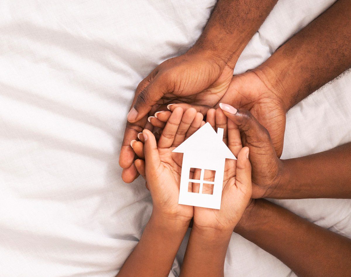 A group of people are holding a paper house in their hands.