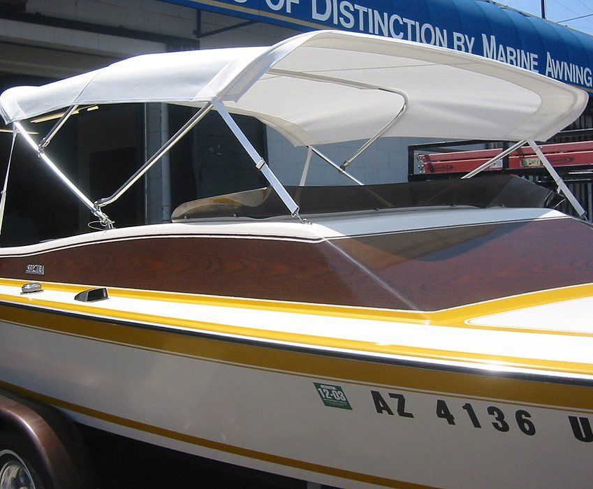 White-and-brown speedboat with a canopy, yellow stripe, and partial registration number on display