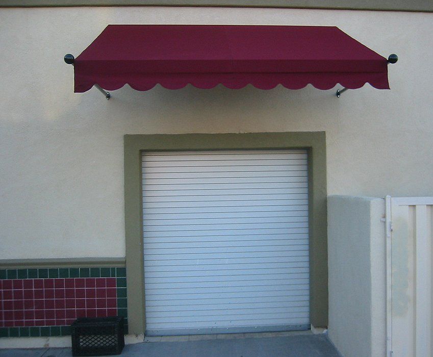 Maroon awning above a closed white roll-up door on a beige building facade