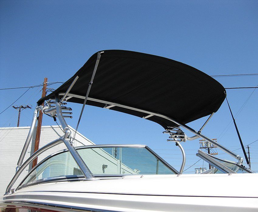 Boat with black bimini top on a clear day against a blue sky