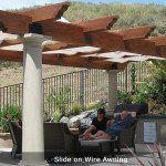 Person sitting on a bench under a wooden pergola beside a pool, with mountains in the background.
