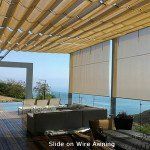 Patio with beige slide-on awning shading modern outdoor seating beside a sea view