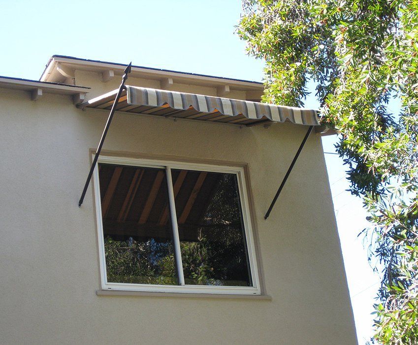 House exterior with a window and striped awning under bright blue sky