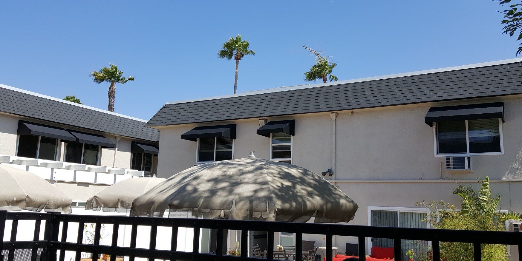 Two-story building with dark roof and windows behind a large rock garden