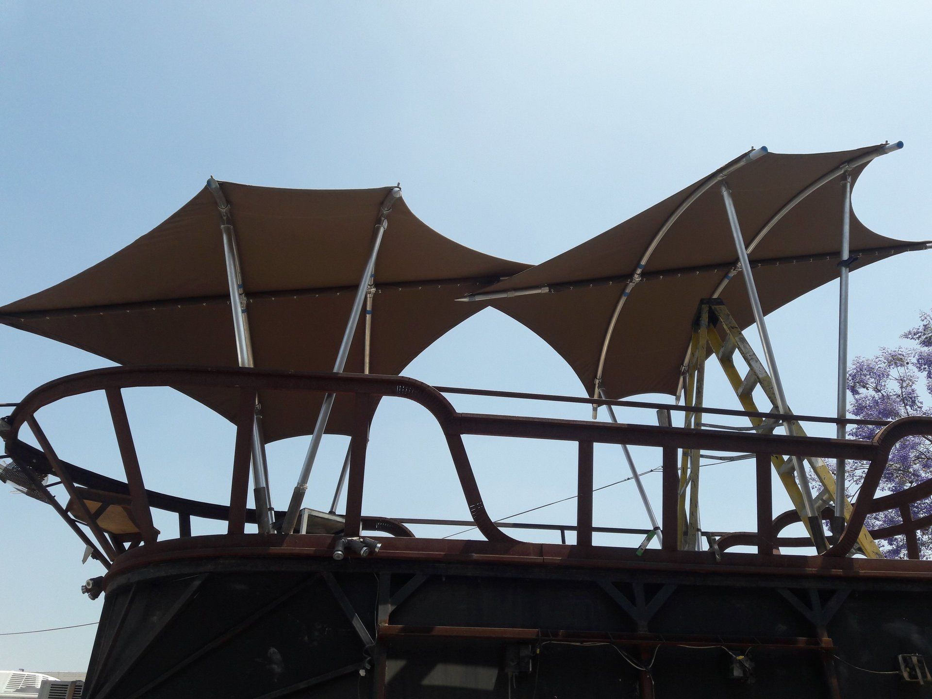 Brown canopies on a metal-frame boat deck against a blue sky
