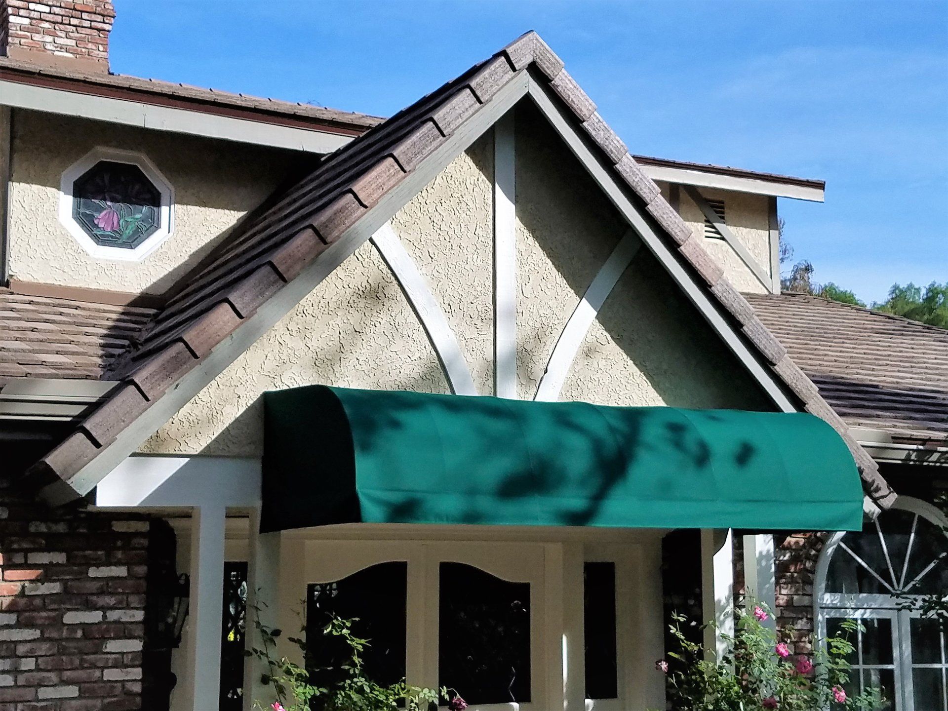 House entrance with a green awning and steep shingled roof