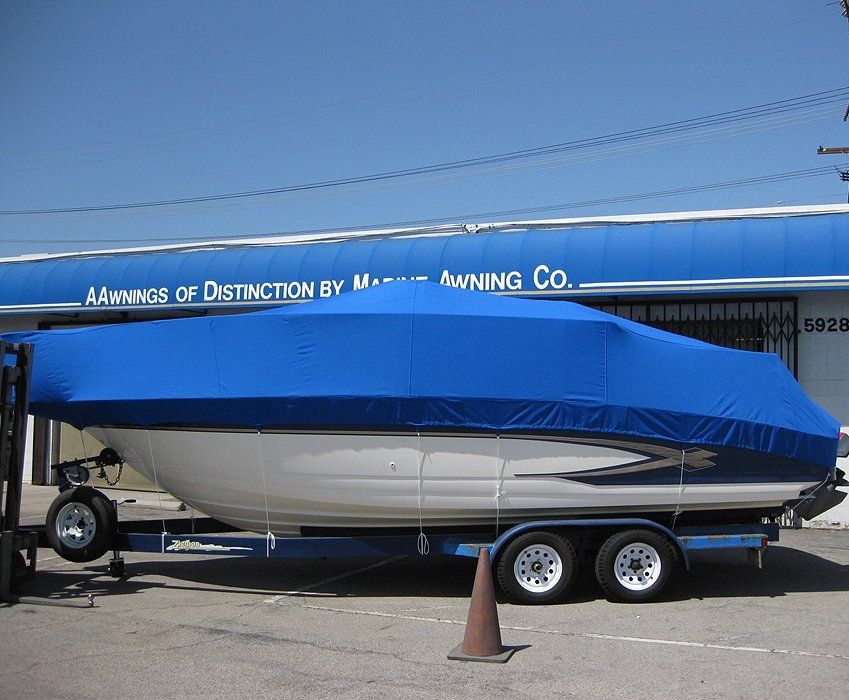Blue and white sailboat on a trailer outside a boat dealership