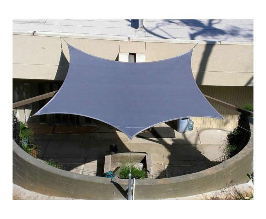 Blue shade sail stretched over a concrete courtyard with circular seating area