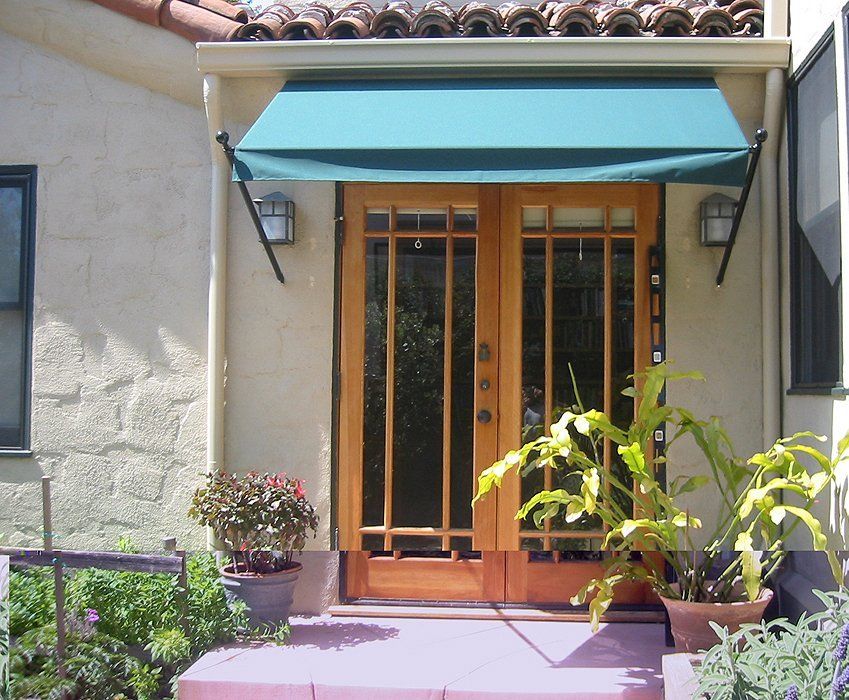 Front entrance with teal awning, wooden double doors, and potted plants on a sunny patio.