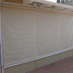 Closed beige outdoor awnings covering a storefront window.