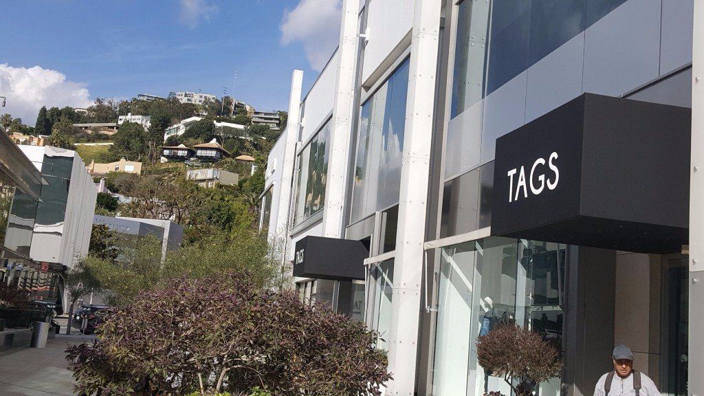 Street with white buildings and an FNGS storefront on a sunny hillside.