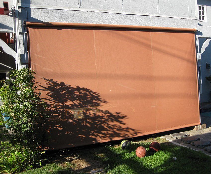 Orange outdoor awning covering a patio, with a grassy yard and two balls in front