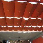 Red-orange ceiling panels with bright light gaps, viewed from below in an indoor room