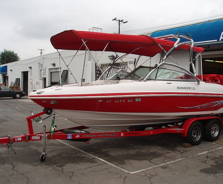 Red and white speedboat on a trailer with a red canopy, parked outdoors on pavement.